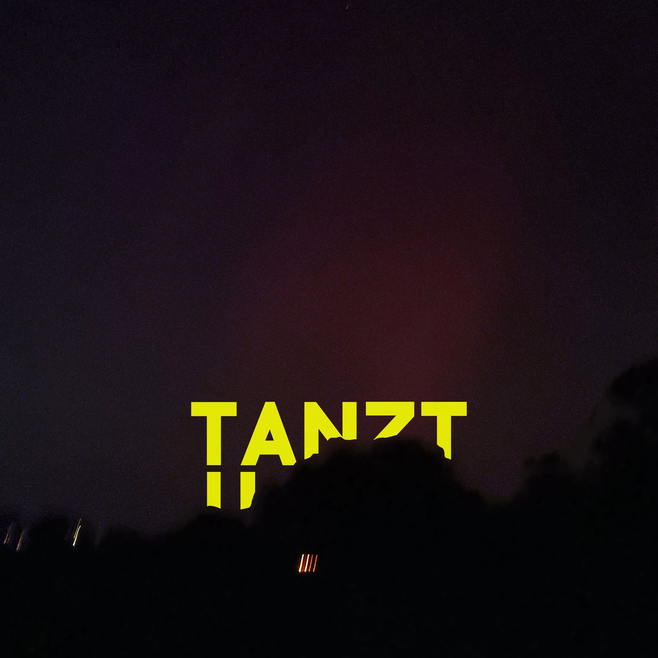 Gelber Schriftzug "Tanzt" vor einem Nachthimmel.